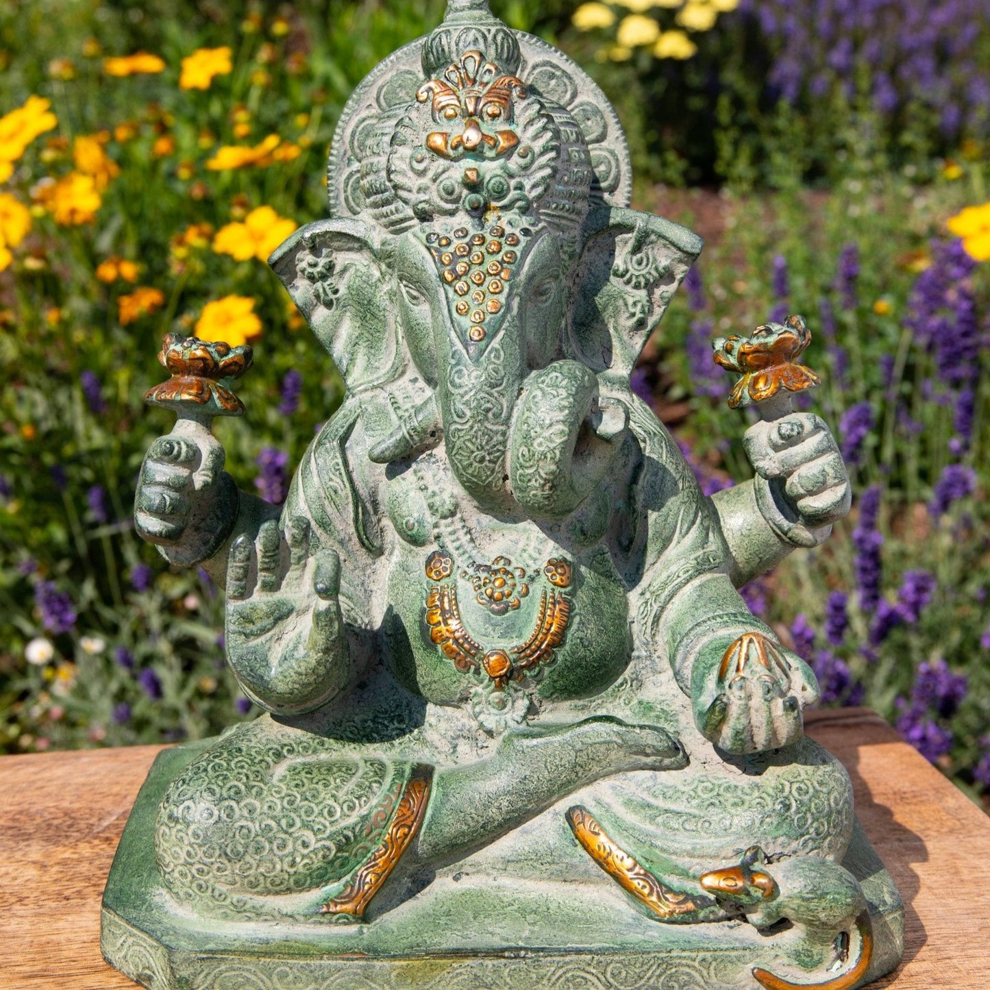 Buddhistischer Gott Ganesha mit Elefantenkopf im Schneidersitz, vier Armen die Gaben halten und einer kleinen Maus am Fuss