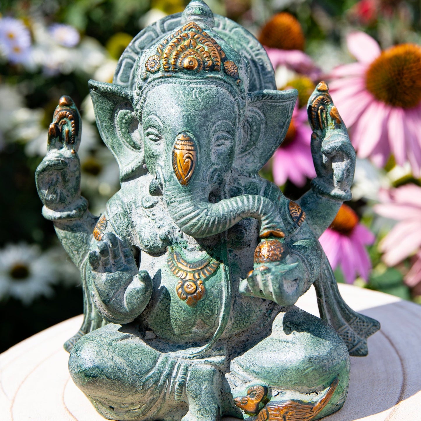 Ganesha mit vier Armen im Schneidersitz und einem runden Bauch, goldene Akzente auf dem sonst grünen Korpus