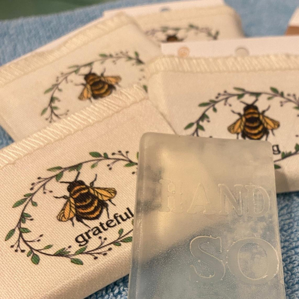 
                  
                    Seife mit kleinen Stoffnbeuteln mit Bienen Druck und kleiner Aufschrift mit unterschiedlichen Wörtern, wie grateul oder strong
                  
                